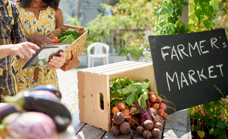 Friendly woman tending an organic vegetable stall at a farmer